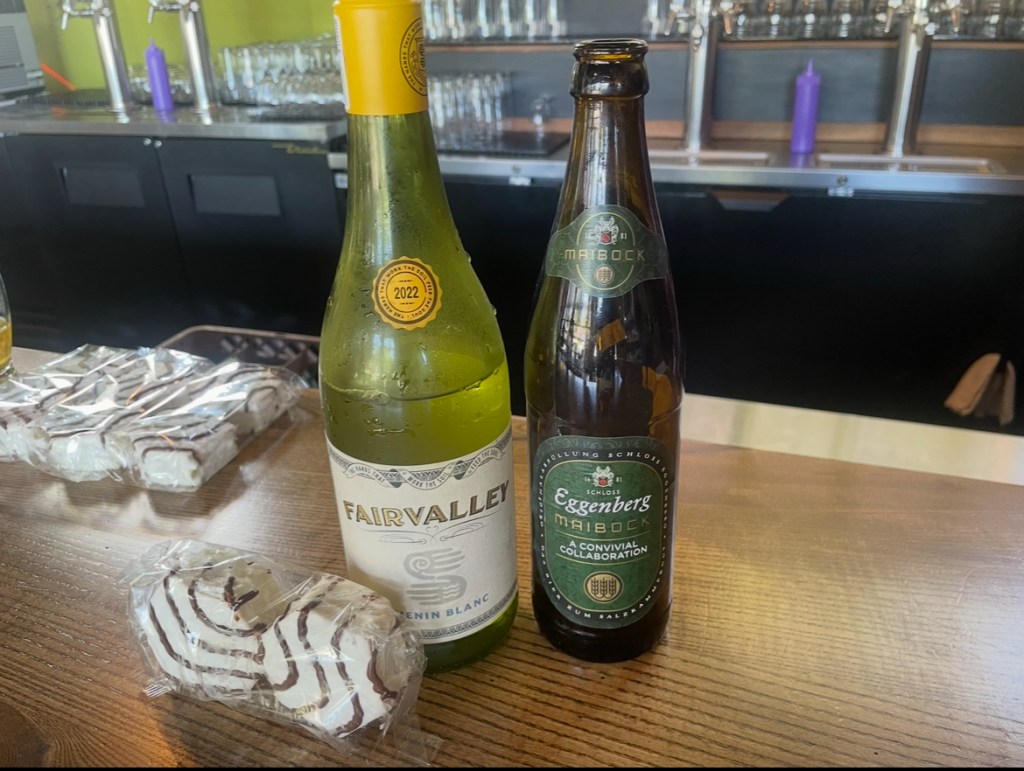 A bottle of wine and a bottle of beer next to Little Debbie Zebra Cakes