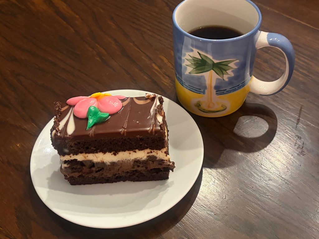 Slice of Cake From Costco Next to a Cup of Coffee